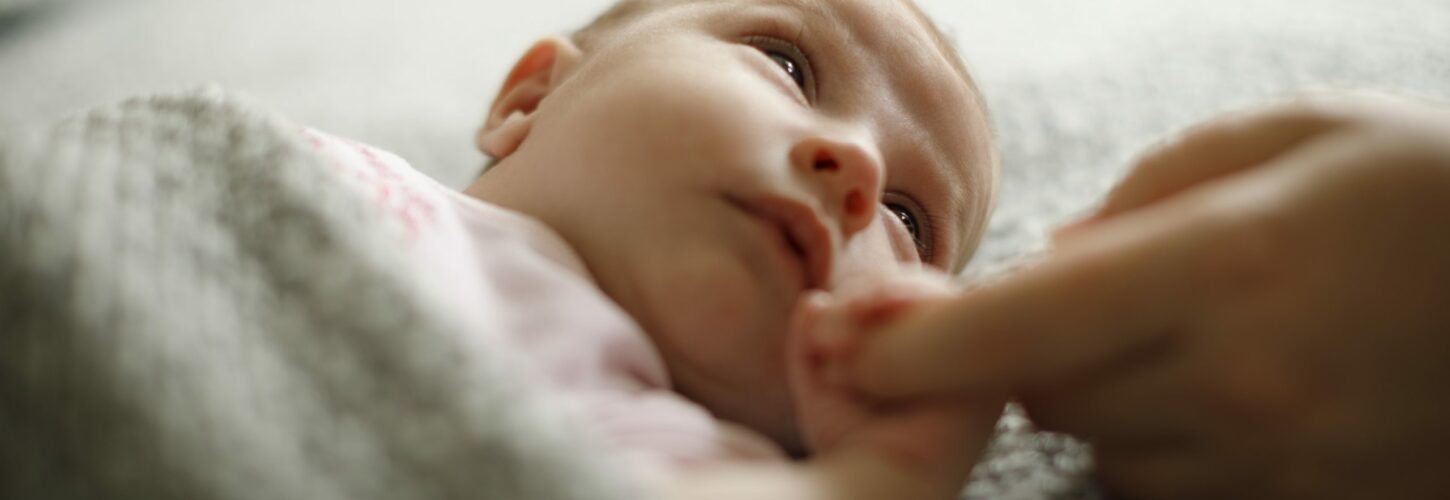 New-born baby holding mother's hand.